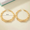 Pair of oversized bamboo hoop earrings in gold with an 8cm diameter measurement.
