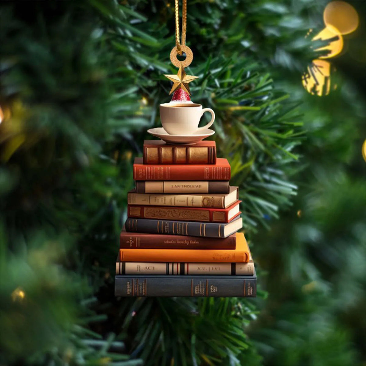 Ornement acrylique doré en forme de livres empilés surmontés d'une tasse de thé, suspendu à une branche d'arbre de Noël vert.