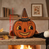 A carved wooden pumpkin decoration with a pointed hat, displayed on a wooden surface.