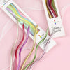 A collection of curved metallic birthday cake candles in various colors is displayed in packaging.