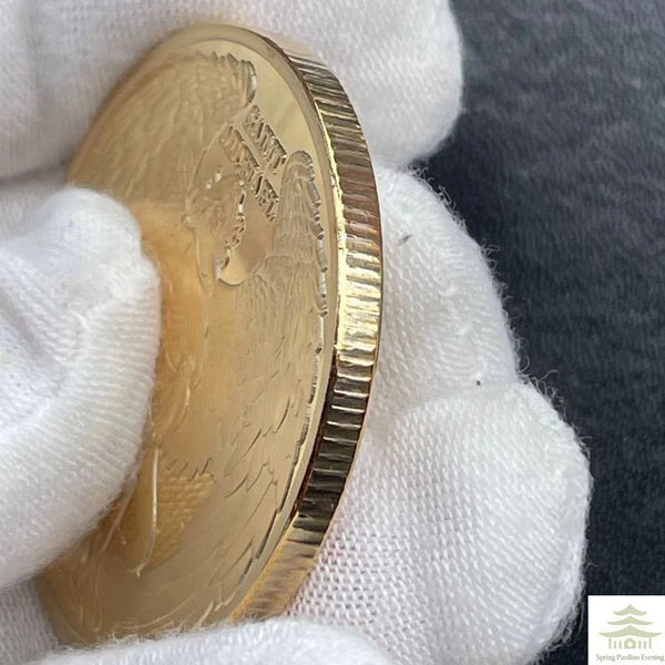 A gold souvenir coin is held in a white glove against a dark background.