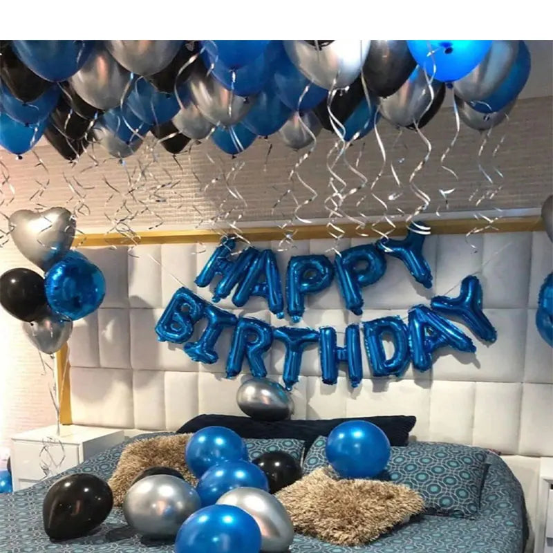 A silver and blue balloon decoration set with the words Happy Birthday hanging against a white wall.