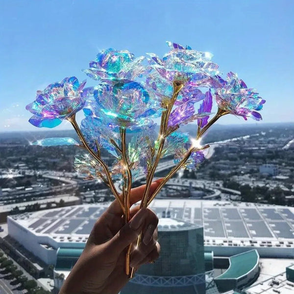 A hand holds a bouquet of iridescent rainbow artificial crystal flowers against an urban skyline backdrop.