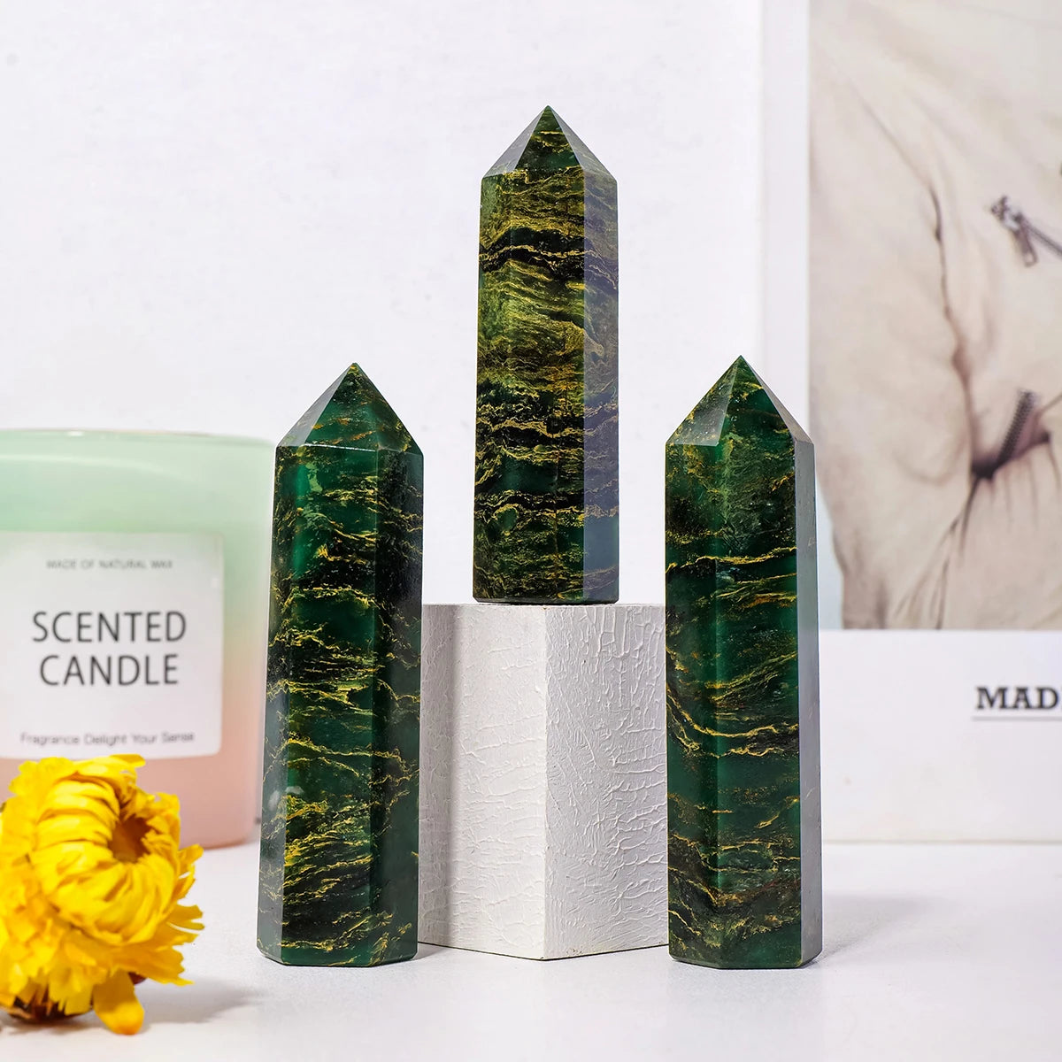 Three dark green emerald crystal point healing wands of varying heights displayed on a white surface.