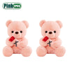 A pair of pink teddy bear plush toys with faux flowers.
