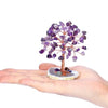 A crystal money tree decor featuring purple amethyst crystals growing from a light stone on a hand.