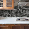 A kitchen countertop with a stainless steel induction cooktop and a dark gray stacked stone backsplash.