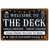 A rustic metal sign with the text Welcome to The Deck Great Friends Great Laughs Proudly Serving Whatever You Bring This is o