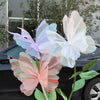 Pink and white 3D mesh butterflies decorating a dark car with green foliage.