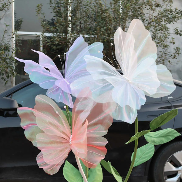 Pink and white 3D mesh butterflies decorating a dark car with green foliage.