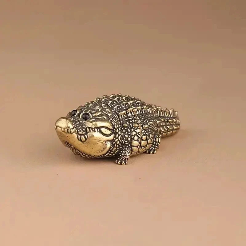 A detailed brass alligator sculpture used as desk decor.