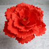 A vibrant orange-red silk foam rose with layered petals and a central yellow stamen.