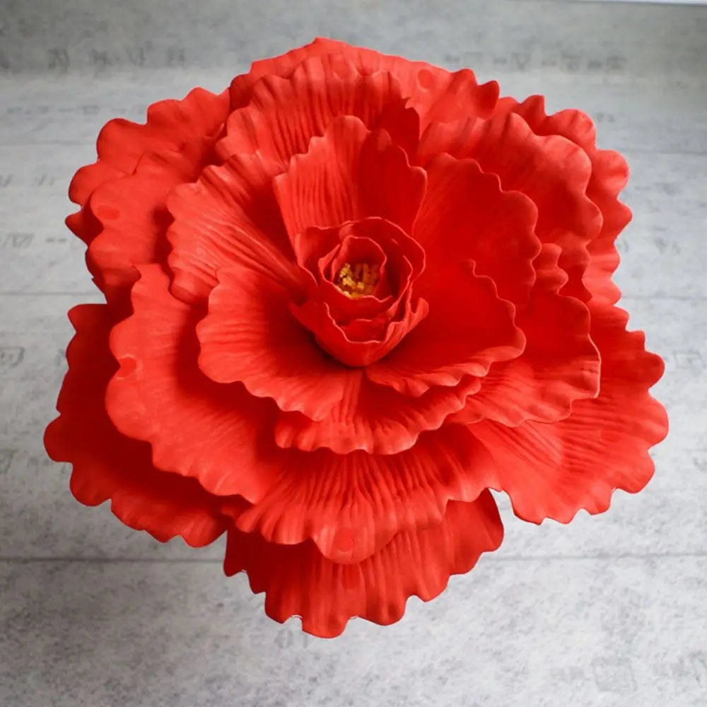 A vibrant orange-red silk foam rose with layered petals and a central yellow stamen.