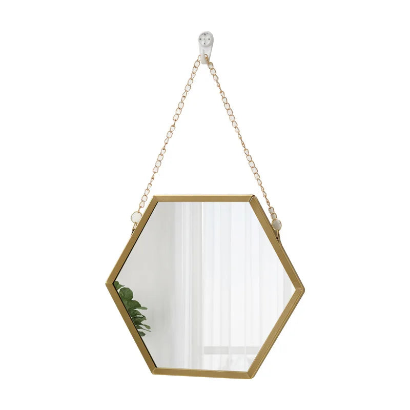 A gold-framed hexagon decorative wall mirror hanging by a chain.