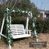 White wooden swing decorated with green ivy garland in an outdoor setting