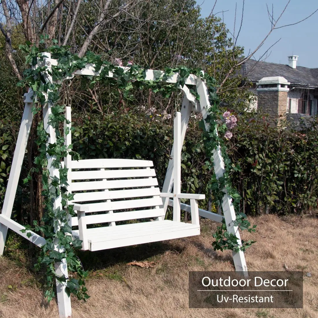 White wooden swing decorated with green ivy garland in an outdoor setting