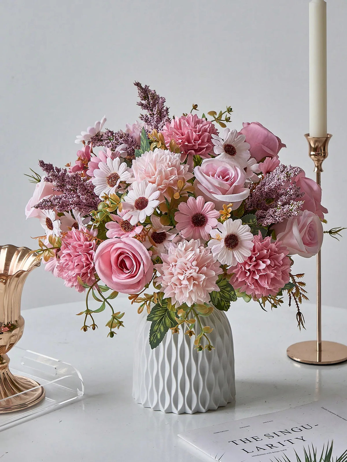 A bouquet of artificial silk pink and purple flowers arranged in a white vase on a table.