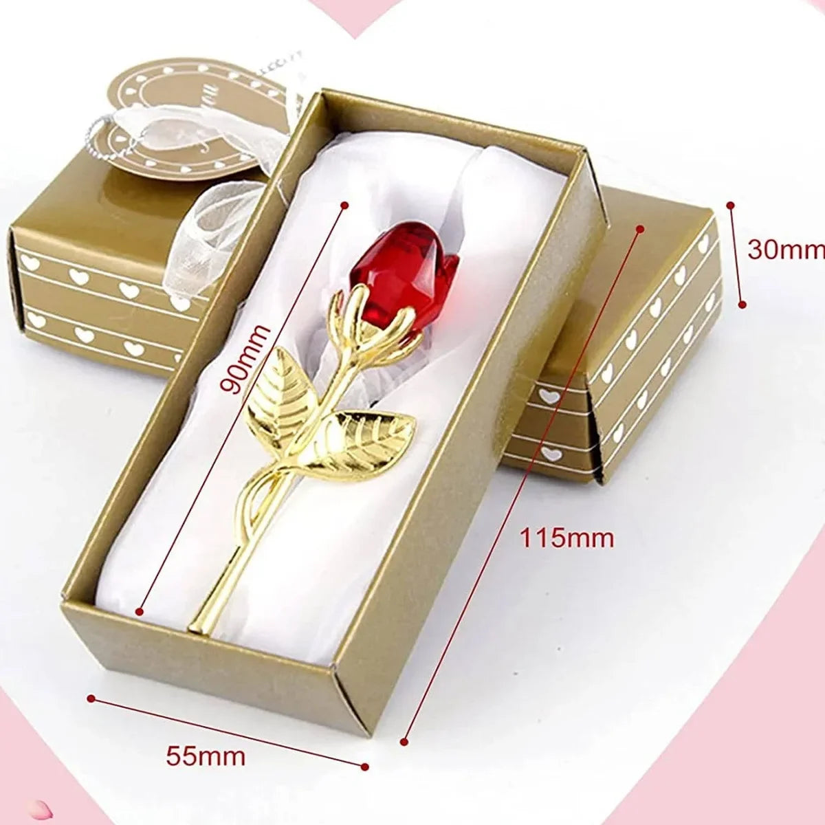 Goldfarbige Box mit künstlicher roter Glasrosenblume auf weißem Papiertüchern.