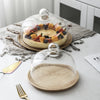 Solid acacia wood cake tray with a glass dome cover displaying fruit and cream