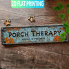 A distressed blue metal sign with the text PORCH THERAPY SESSION IN PROGRESS is displayed on a wooden surface.