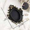 A black vintage baroque resin hanging photo frame displayed on a white surface with pearl accents.
