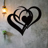 Black metal wall art featuring a stylized heart design with a smaller heart inside, mounted on a gray concrete wall.