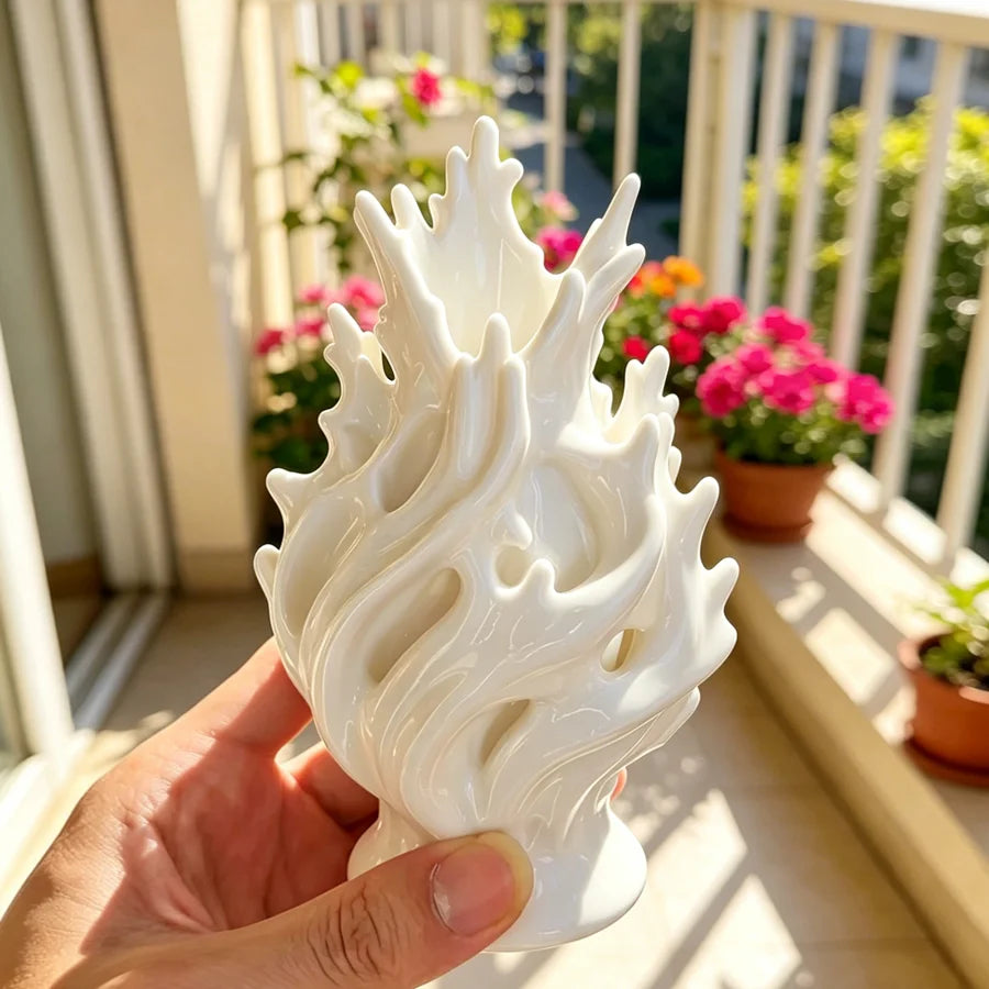 A hand holds a white, sculpted plastic flower vase with wavy lines against a bright outdoor background.