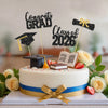 A white graduation cake decorated with black and gold glitter toppers, including 'Congrats Grad' and 'Class of 2026'.