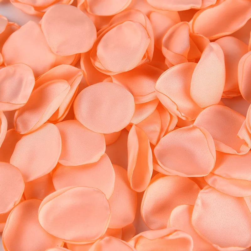 A close-up of soft peach colored silk rose petals scattered on a surface.