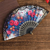 A Spanish style folding lace trim handheld fan featuring vibrant floral patterns and black detailing.
