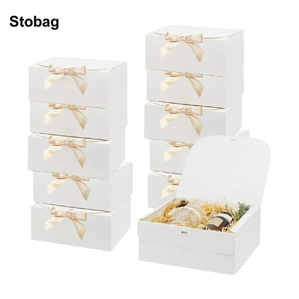 White gift boxes with gold ribbon ties and natural filler displayed on a white background.