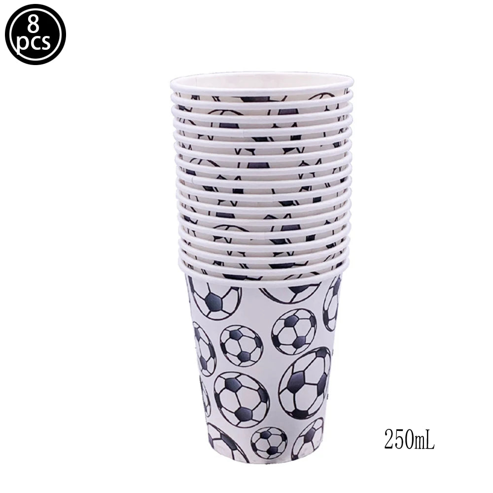 A set of eight black and white soccer ball cake toppers in a cylindrical container.