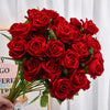 A bouquet of deep red velvet artificial roses with green leaves.