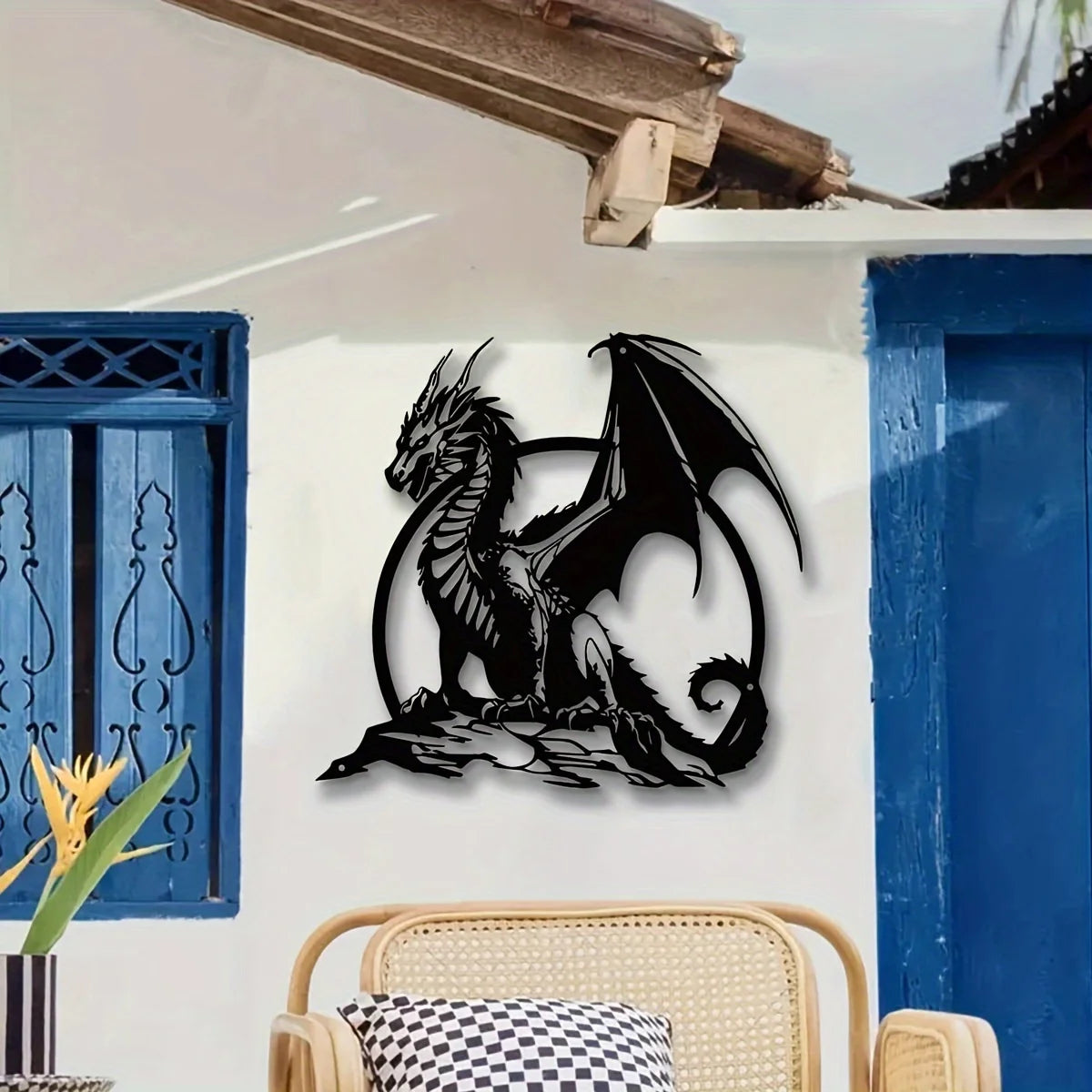 A black metal dragon wall sculpture mounted on a white exterior wall next to a blue wooden door.