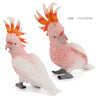 Pink resin parrot figurine with orange crest, shown in a side view.