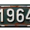 A vintage, weathered green aluminum license plate with the year 1964 embossed in white numerals.