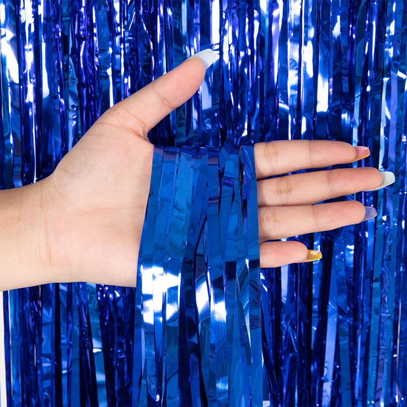 A hand holds blue metallic tinsel foil fringe curtain backdrop for parties.