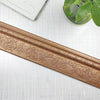 A close-up of a gold-colored self-adhesive 3D wall trim line featuring an ornate floral pattern.