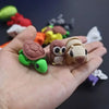 A hand holds several small, articulated 3D printed animal figurines including a green turtle, a brown owl, and a beige mammal