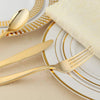 A set of gold disposable cutlery including forks, spoons, and knives arranged on a plate.