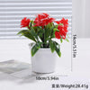 A potted artificial red rose plant with green leaves shown on a white surface.