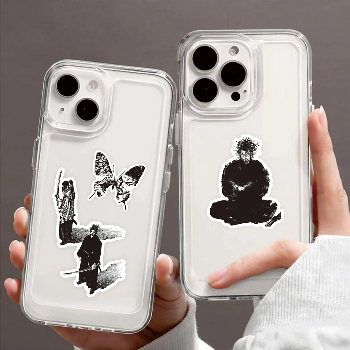 Eine Hand hält eine klare Handyhülle mit schwarzen Silhouetten-Cartoon-Aufklebern von Figuren und Schmetterlingen.