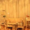 A cozy interior decorated with yellow fairy curtain string lights illuminating a sofa and display shelves.