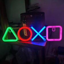 Neon wall art featuring a triangle, circle, and box icons in green, orange, and blue light.
