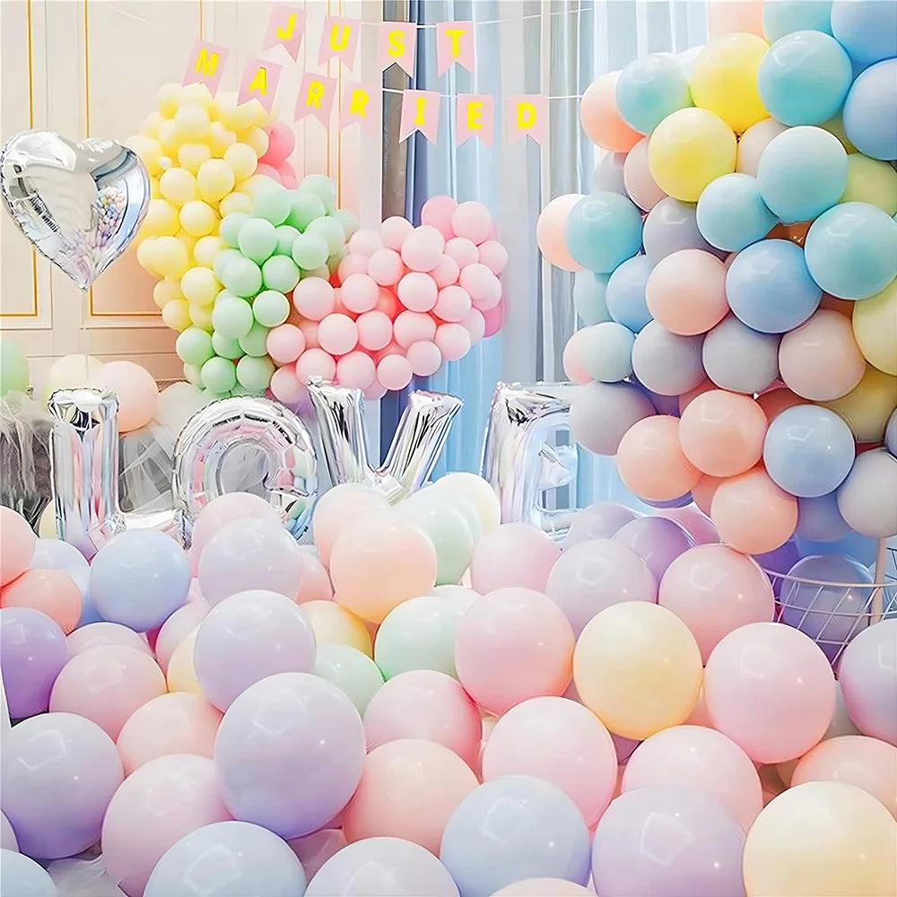 A large arrangement of pastel rainbow latex balloons in various shades of pink, yellow, green, and blue for party décor.