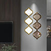 Decorative acrylic mirror wall stickers in gold and olive green tones mounted on a gray wall.
