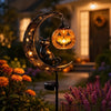 A solar-powered pumpkin moon garden stake light featuring a carved pumpkin face and a silhouette of a cat on a crescent moon.