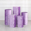 A collection of purple spandex cylinder stands used for weddings and events, displayed against a white wall.