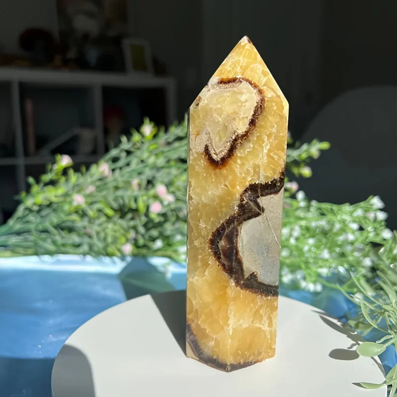 Tour de cristal jaune clair avec inclusions sombres sur une assiette blanche.