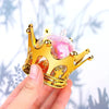 A hand holds a gold crown with pink and clear candy boxes, set of twelve.